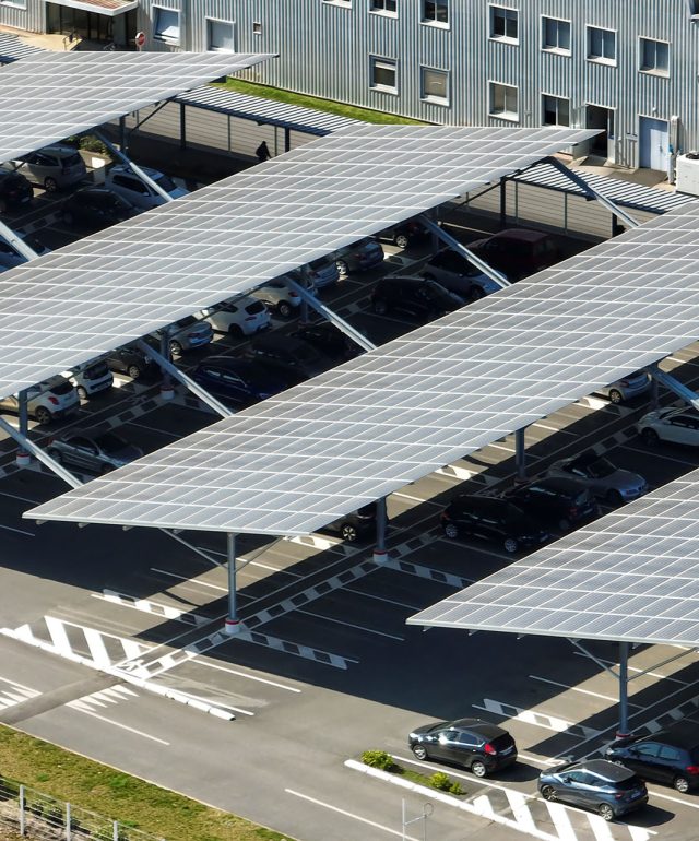 Aerial view of solar panels installed over parking lot with parked cars for effective generation of clean energy
